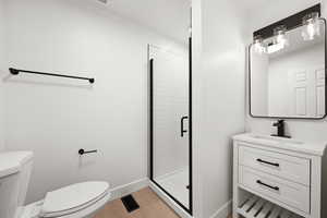 Bathroom with a shower with shower door, toilet, and vanity