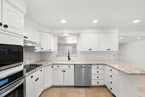 Kitchen with sink, white cabinets, appliances with stainless steel finishes, and kitchen peninsula