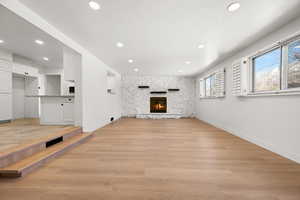 Unfurnished living room featuring light hardwood / wood-style flooring, a fireplace, and a textured ceiling