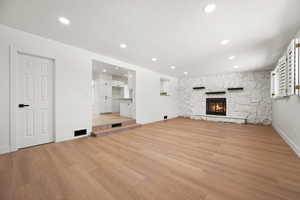 Unfurnished living room with a fireplace, light wood-type flooring, and a textured ceiling