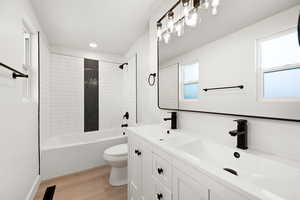 Full bathroom featuring vanity, toilet, tiled shower / bath, and wood-type flooring