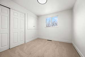 Unfurnished bedroom featuring a closet and light colored carpet