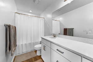 Full bathroom with vanity, hardwood / wood-style flooring, shower / bath combo, and toilet