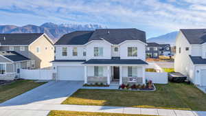 View of front of home with a garage, a front lawn, a mountain view, and covered porch