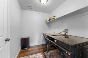 Clothes washing area with dark hardwood / wood-style flooring and washing machine and clothes dryer