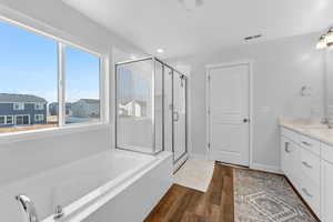 Bathroom featuring hardwood / wood-style floors, vanity, and plus walk in shower