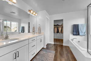 Bathroom featuring vanity, a bathing tub, and wood-type flooring