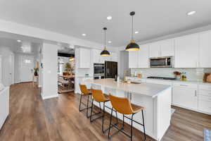 Kitchen with sink, stainless steel appliances, white cabinets, and a center island with sink