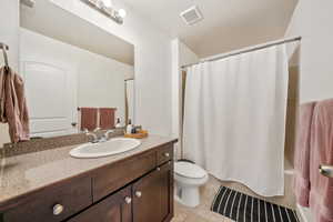 Full bathroom featuring tile patterned flooring, toilet, a textured ceiling, vanity, and shower / tub combo with curtain