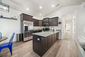 Kitchen featuring appliances with stainless steel finishes, dark brown cabinets, decorative light fixtures, sink, and kitchen peninsula