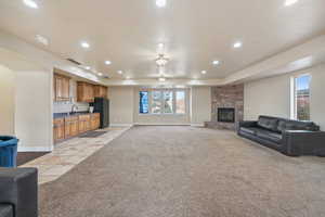 Living room with light colored carpet, plenty of natural light, and a stone fireplace