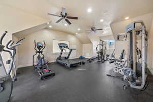 Gym with ceiling fan, a textured ceiling, and lofted ceiling