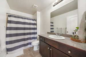 Bathroom with a textured ceiling, tile patterned floors, vanity, and toilet