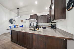 Kitchen featuring kitchen peninsula, light hardwood / wood-style flooring, hanging light fixtures, and stainless steel appliances