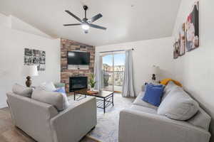 Living room with ceiling fan, light hardwood / wood-style flooring, lofted ceiling, and a fireplace