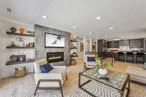 Living room featuring a textured ceiling, light hardwood / wood-style floors, and a fireplace