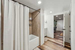 Bathroom with vanity, shower / bathtub combination with curtain, and wood-type flooring