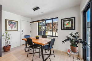 Dining room with light hardwood / wood-style floors and a textured ceiling