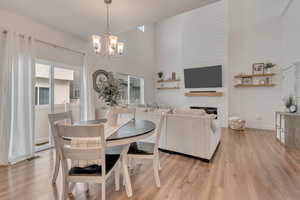 Dining space with a fireplace, light wood-type flooring, and an inviting chandelier