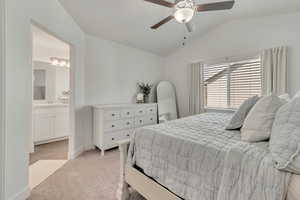 Bedroom featuring lofted ceiling, connected bathroom, sink, ceiling fan, and light colored carpet