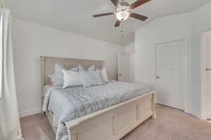 Bedroom featuring ceiling fan, light carpet, and lofted ceiling