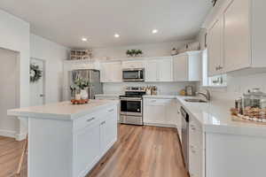 Kitchen featuring white cabinets, appliances with stainless steel finishes, a kitchen island, light hardwood / wood-style floors, and sink