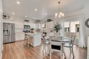 Dining area with sink, light hardwood / wood-style flooring, and a chandelier