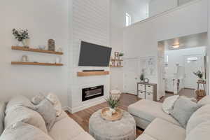 Living room with a large fireplace, hardwood / wood-style flooring, and a towering ceiling