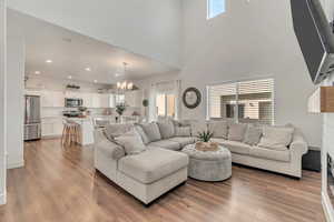 Living room with hardwood / wood-style flooring, a notable chandelier, a high ceiling, and a wealth of natural light