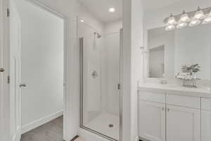 Bathroom with hardwood / wood-style floors, an enclosed shower, and vanity