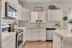 Kitchen featuring sink, white cabinetry, appliances with stainless steel finishes, and light hardwood / wood-style flooring