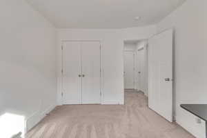 Unfurnished bedroom featuring a closet and light colored carpet