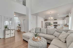 Living room with a towering ceiling, a chandelier, and light wood-type flooring