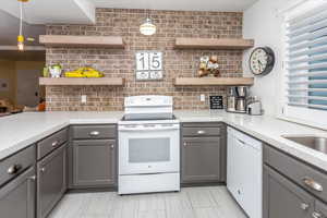 Kitchen with pendant lighting, white appliances, and gray cabinets