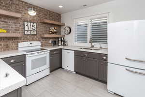 Kitchen with backsplash, light stone countertops, sink, and white appliances