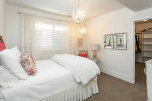 Bedroom with a closet, a walk in closet, a chandelier, and carpet flooring