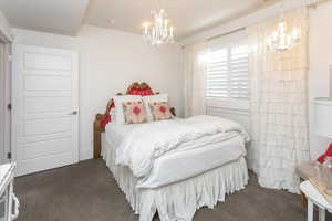 Bedroom with an inviting chandelier and dark carpet