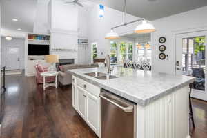 Kitchen featuring pendant lighting, stainless steel dishwasher, a center island with sink, and white cabinets