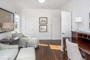 Home office with dark hardwood / wood-style floors and crown molding