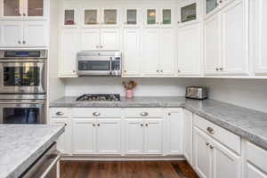 Kitchen with dark wood flooring, stainless steel appliances, and white cabinetry