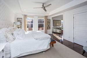 Bedroom featuring ceiling fan, dark hardwood / wood-style floors, ornamental molding, and a raised ceiling