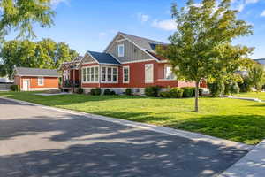 View of side of house with a front yard and an outbuilding