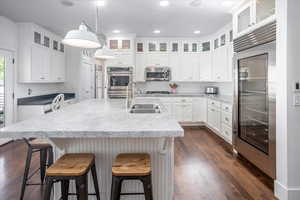 Kitchen featuring stainless steel appliances, sink, white cabinets, and an island with sink