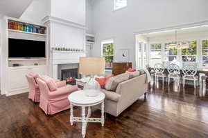 Living room with dark hardwood / wood-style floors, a notable chandelier, a towering ceiling, and a fireplace