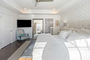 Bedroom with ceiling fan, dark hardwood / wood-style floors, crown molding, and a raised ceiling