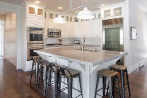 Kitchen with white cabinetry, a center island with sink, stainless steel appliances, a breakfast bar, and sink