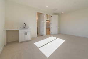 Unfurnished bedroom with sink and light carpet