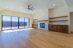 Unfurnished living room with a mountain view, ceiling fan, a tile fireplace, and light hardwood / wood-style floors