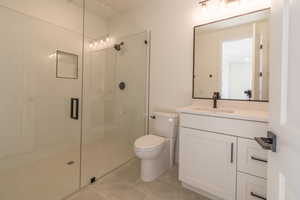 Bathroom featuring toilet, walk in shower, vanity, and tile patterned flooring