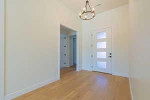 Foyer entrance with an inviting chandelier and light hardwood / wood-style floors